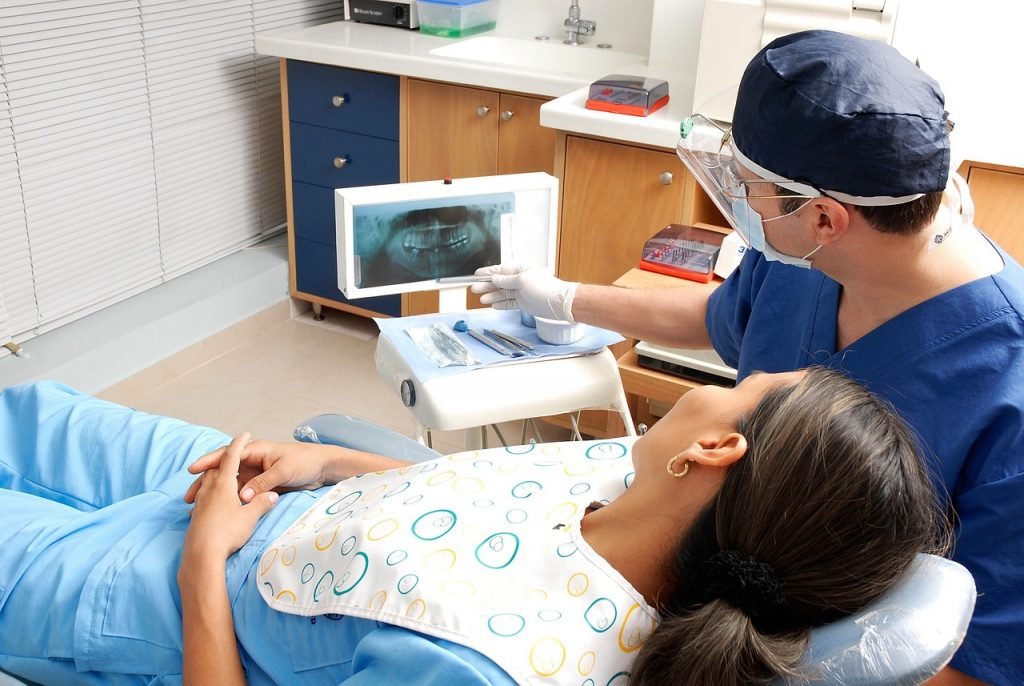 Dentista mira a una placa con su paciente por las caries en los dientes