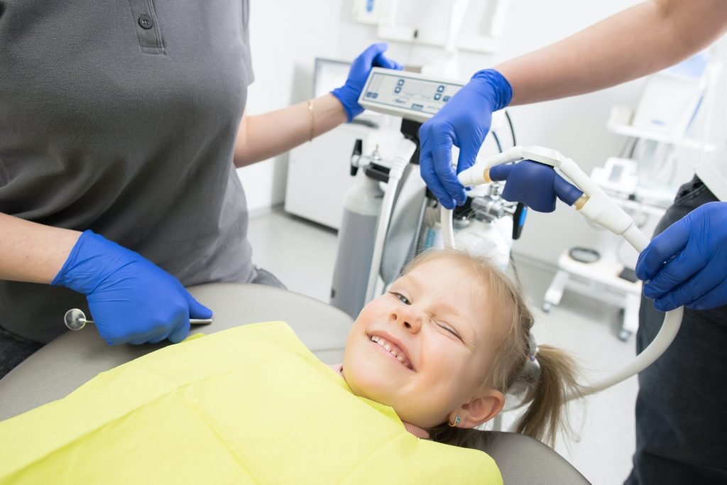 Niña sonríe mientras es tratada por las caries en los dientes
