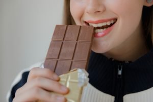 Chica comiendo chocolate, no cuidando muy bien su salud bucal