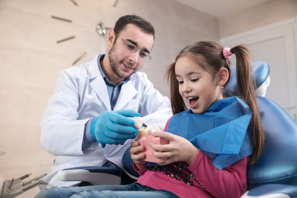 Niña tratandose con el odontologo por caries en niños